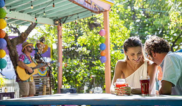 A young couple enjoys soft drinks outdoors in Islamorada while listening to a singer with a guitar